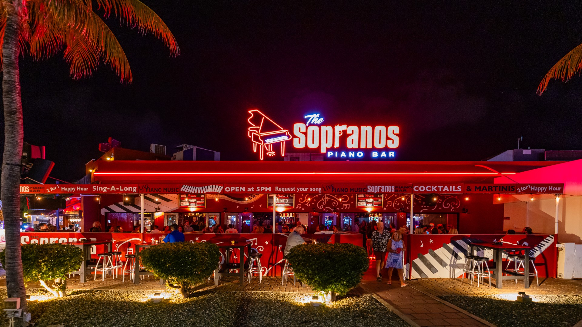 Illuminated exterior of Sopranos Piano Bar at night in Aruba.