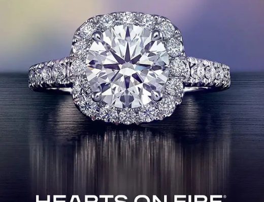 Hearts On Fire promotional image showing a large center diamond ring with a surrounding halo and diamond-set band at Noble Jewelers in Aruba.