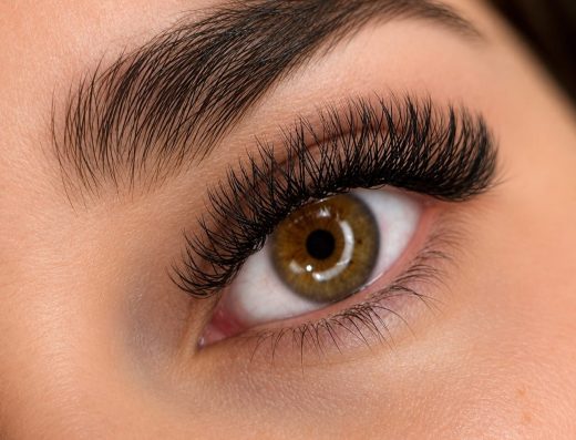 Close-up of a brown eye with full dark eyelashes and a groomed eyebrow for Aruba Tanning Lashes.
