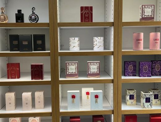 Shelves inside Dubai Shop Aruba displaying boxed perfumes in red, pink, white, purple and other packaging.